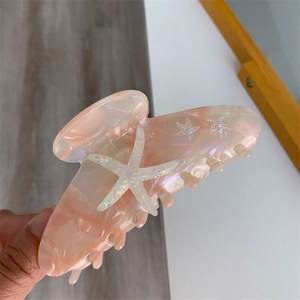 Detail view of pink marble acetate hair claw clip featuring sparkling starfish motifs
