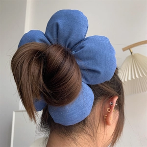 Detail of a large 3D blue denim flower hair scrunchie worn on a bun hairstyle