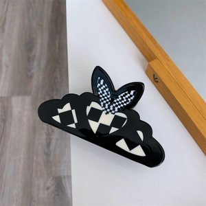 Detailed view of the wavy black hair claw clip featuring stylish checkered heart motifs