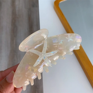 Detail of large acetate hair claw featuring iridescent starfish charms and glossy finish
