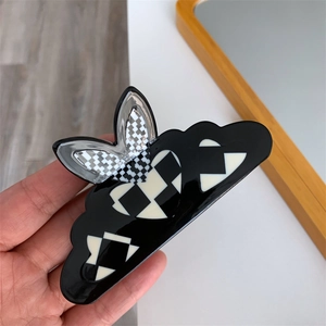 Detail of bunny ear checkerboard hair claw with black white heart pattern and wave edges