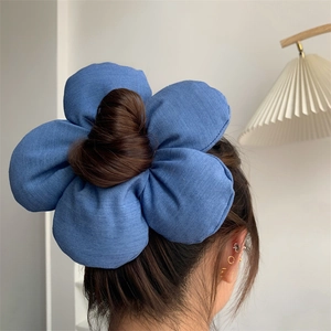 Detailed back view of a large blue denim flower hair scrunchie styled on a bun