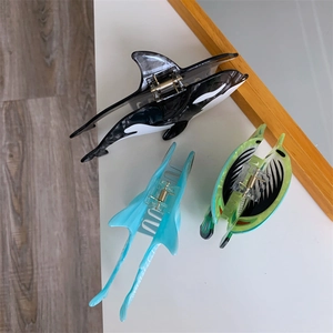 Macro detail of ocean-themed acetate hair clips in orca and manta ray animal shapes