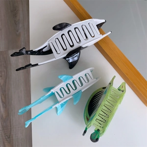 Detailed top view of three ocean animal acetate hair claws including whale and shark designs