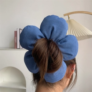 Detail view of large denim blue fabric flower hair tie used for styling a messy bun