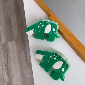 Detail of green dinosaur hair claw clip with white acetate splicing and sparkly rhinestones