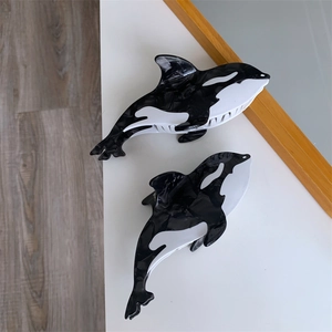 Detail of large and small orca-shaped acetate hair claws with black and white marble texture