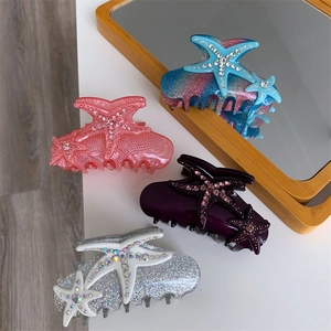 Glittering starfish hair claws with rhinestones in blue, pink, and purple acetate