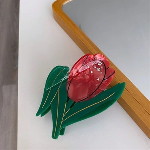 Détail de la pince à cheveux tulipe avec marbrure rouge, strass et feuilles vertes