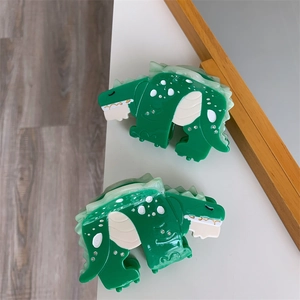 Detail view of green acetate dinosaur hair claw clip with rhinestones on a white desk