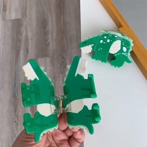Detail of green acetate dinosaur hair claw clip showing internal mechanism and side view