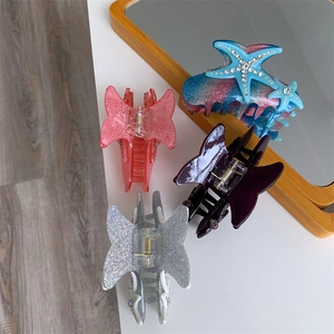 Detailed view of handmade starfish and butterfly hair claws with rhinestone accents