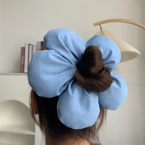 Detail of oversized light blue fabric flower scrunchie on a bun hair style