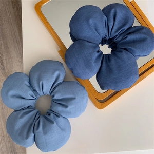 Macro detail of large denim fabric flower hair ties showing twill texture and stitching