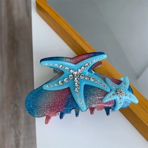 Macro detail of starfish hair claw with gradient blue glitter and inlaid rhinestones
