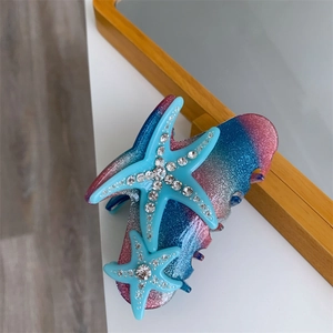 Close-up of pink and blue gradient glitter hair claw with rhinestone starfish detail