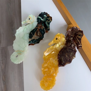 Detailed macro view of two unique seahorse-shaped hair clips with marble acetate textures