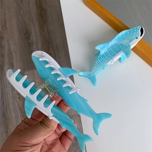 Detail showing a blue shark-shaped hair claw with realistic ocean pattern and metal spring