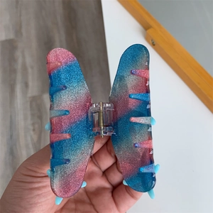 Detail of blue and pink gradient butterfly hair claw clip with shimmering glitter finish