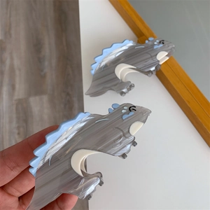 Detailed macro view of dinosaur-shaped hair claw clips with grey marble texture finish