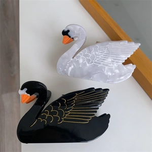 Elegant swan acetate hair claw clips in black and white with gold-lined feather details