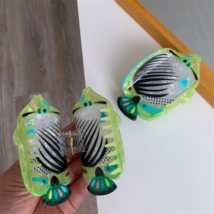 Detail of fish-shaped green acetate hair claw with hand-painted dots and gold metal spring