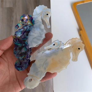 Unique seahorse-shaped acetate hair claws with marble texture and golden line details