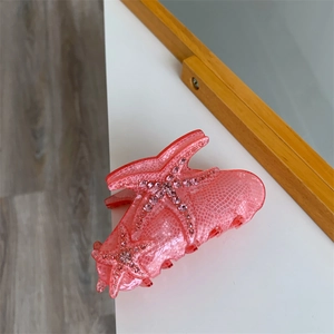 Detail of pink acetate hair claw clip with crystal starfish and scale texture patterns