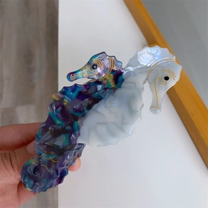 Close-up of seahorse acetate hair claw clip with colorful marble pattern and gold edges