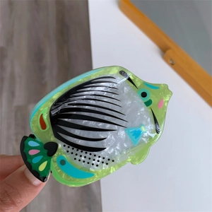 Detail showing tropical fish acetate hair claw clip with pearlescent white and green finish