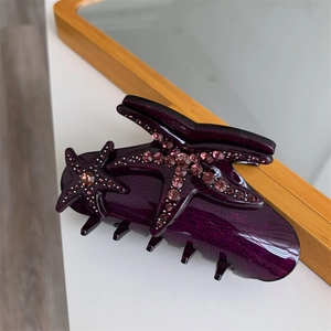 Macro detail of purple acetic acid hair claw clip with starfish and rhinestone textures