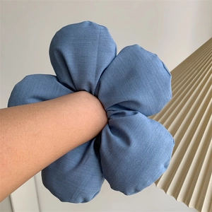 Detail of a large blue denim fabric flower hair scrunchie worn on a wrist