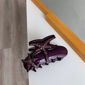 Close-up of a purple starfish claw clip featuring pink rhinestones and a polished finish