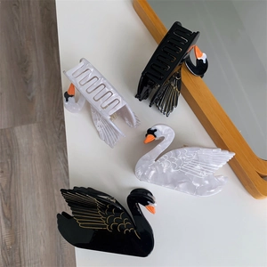 Detailed overhead view of swan-shaped acetate hair claws with gold-painted wing patterns