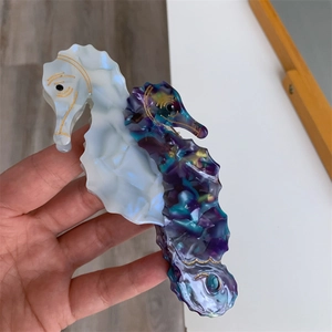 Detailed close-up of seahorse acetate hair claw clip with pearly white and marble finish