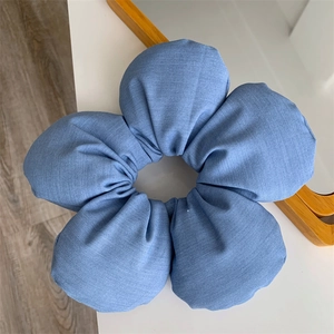 Detail of blue denim sponge flower hair scrunchie showing fabric texture and large petals