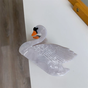 Detail of elegant swan hair claw clip with white marble pattern on acetate material