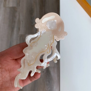 Detail of a large acetate jellyfish hair claw clip with pearlescent pink and white textures