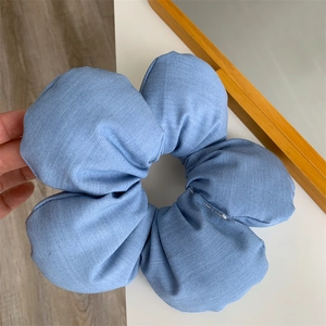 Detailed close-up of large blue denim-textured flower hair scrunchie with five petals