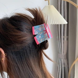 Modern acetate hair claw clip with pink marble texture shown on a woman hairstyle