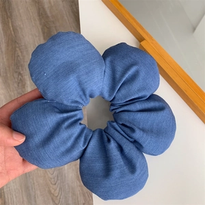 Detail of the denim blue fabric texture on the oversized five-petal flower hair scrunchie