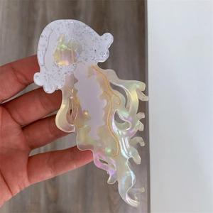 Detail of cream white jellyfish hair claw clip with iridescent tentacles and gold accents