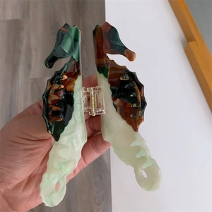 Close-up of seahorse hair claw clip with marble green acetate and golden spring