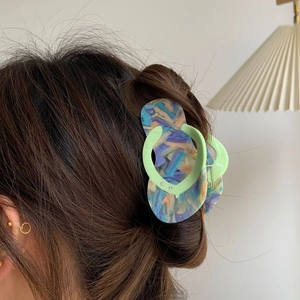 Acetate hair claw clip in flip-flop sandal shape with colorful marble pattern on hair