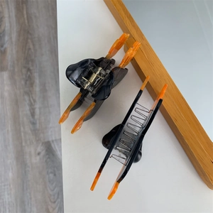 Détail de la pince à cheveux Halloween avec base noire et ailes de papillon orange