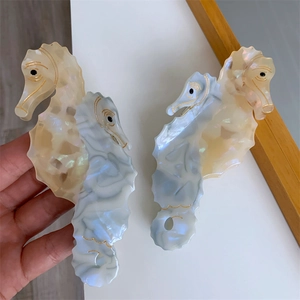 Detailed seahorse hair claw clips in pearlescent cream and marble blue acetate finish