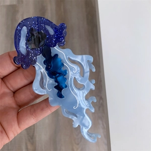 Macro detail of a jellyfish hair claw clip with blue glitter finish and white wave patterns
