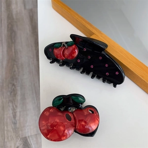 Detailed close-up of creative cherry hair clips with rhinestones and red marble texture