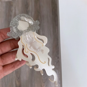 Macro detail of large cream jellyfish hair claw clip with silver glitter and gold accents