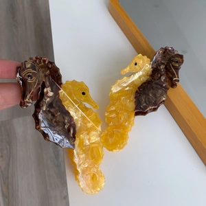 Detail of seahorse acetate hair claw showing unique marble texture and golden accents
